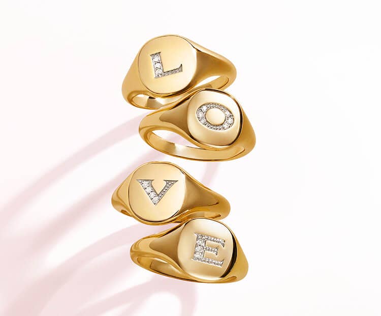 An image of 4 gold pinky rings spelling LOVE.