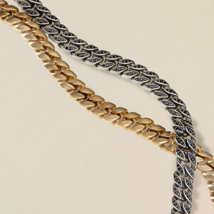 An image of two mens curb chain necklaces. One in 18K yellow gold and the other in sterling silver with pave black diamonds.