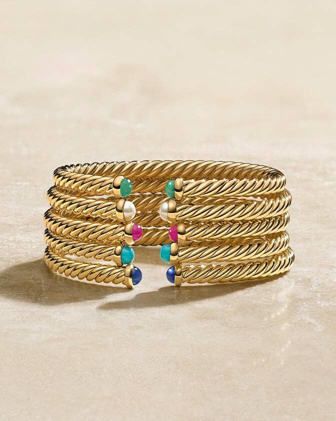 Stack of gold David Yurman cable bracelets with a variety of stones.