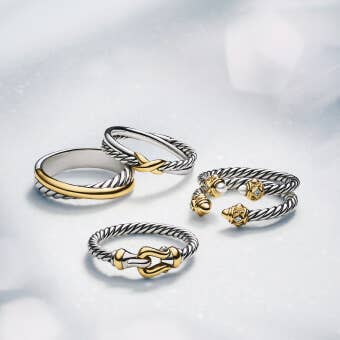 A selection of David Yurman rings in silver, gold, and mixed metals.
