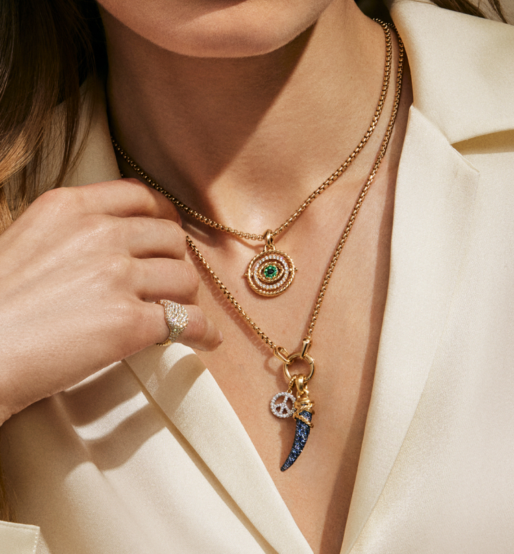Model wearing two yellow gold box chains with 3 gold amulets.