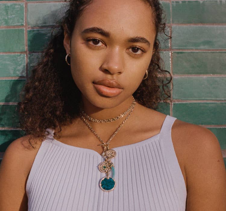 An image of Chandler Kinney wearing gold chain and multiple amulets.