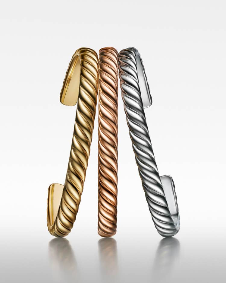 Three David Yurman Men's Sculpted Cable bracelets in yellow gold, silver, and rose gold.