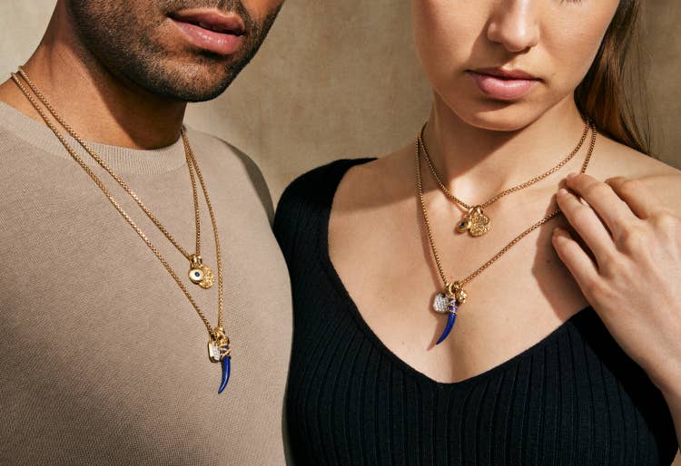 A man and woman both wearing gold David Yurman necklaces with multiple Unisex Amulets.
