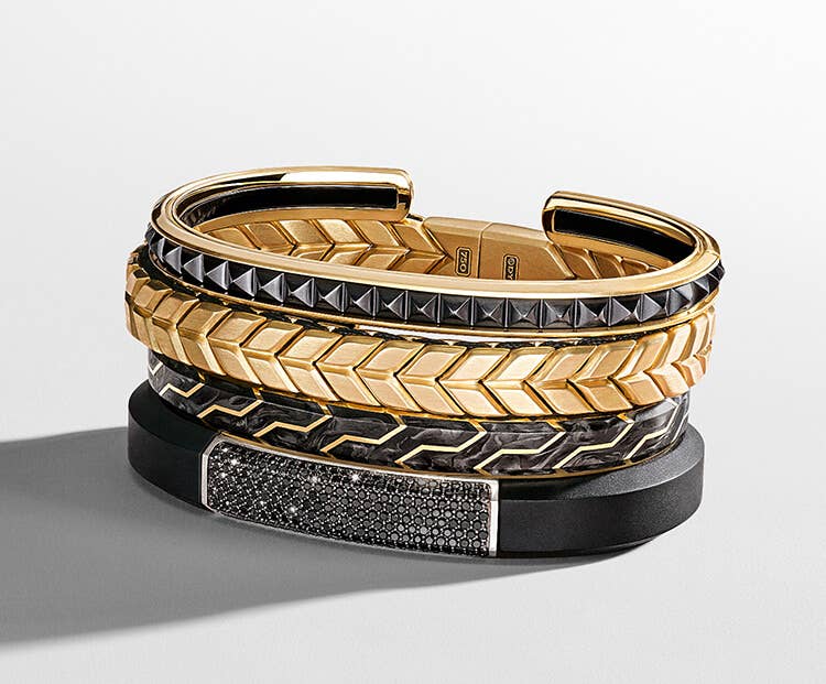 An image of 4 mens black and gold bracelets.