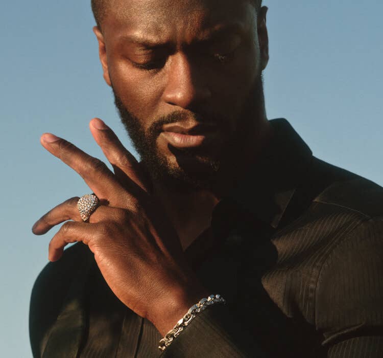 An image of Aldis Hodge wearing pavé ring and faceted bracelet..