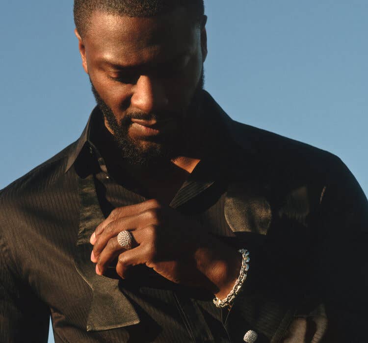 An image of Aldis Hodge wearing pavé ring and faceted bracelet..