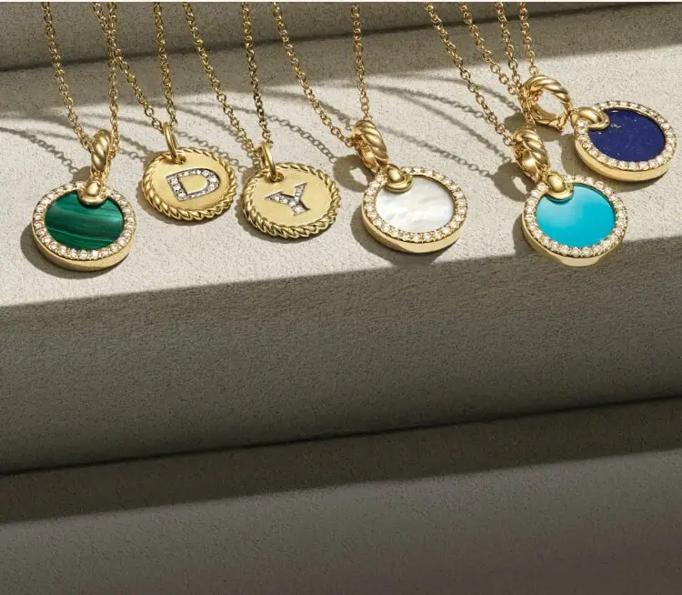 A selection of David Yurman amulets and pendants on gold chains.