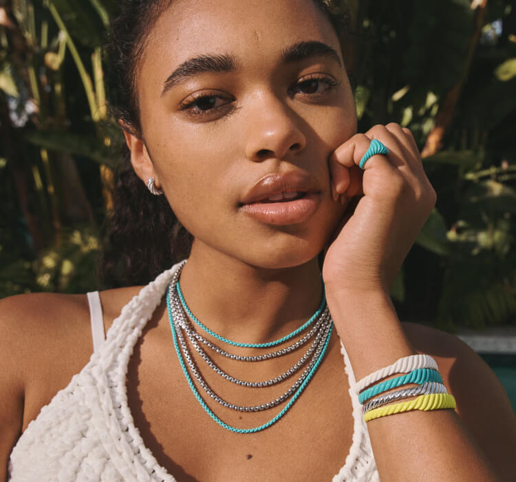 An image of Chandler Kinney wearing sculpted cable enamel bracelets and rings.