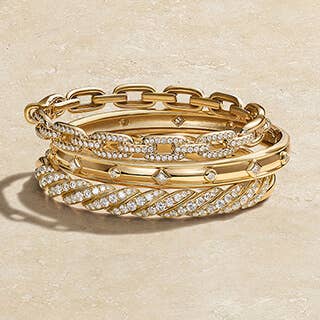 A stack of gold David Yurman women's bangle bracelets with and without diamonds.