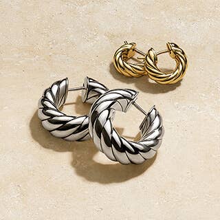 One silver and one gold pair of David Yurman hoop earrings.