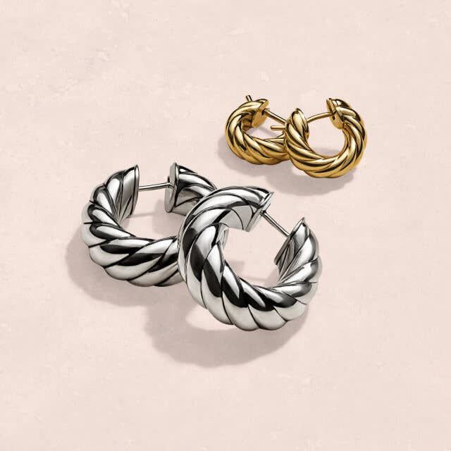 One silver and one gold pair of David Yurman hoop earrings.