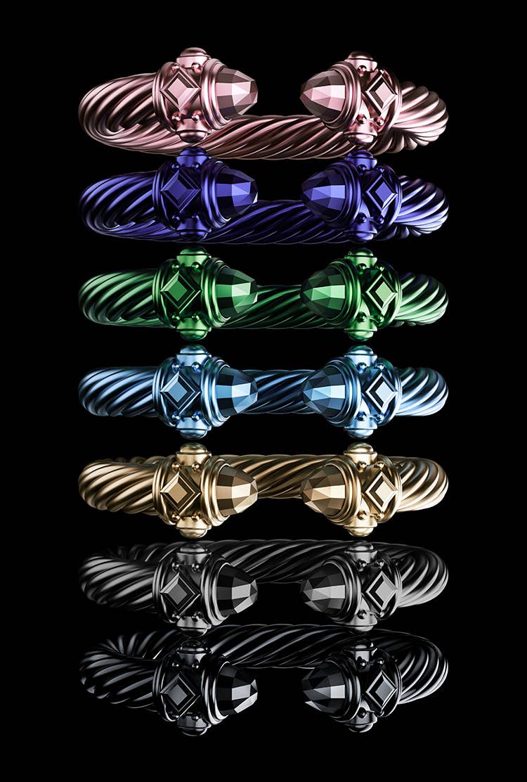 An image of a seven David Yurman Renaissance aluminum Cable bracelets lined up in a horizontal row against a black background. Each bracelet is shown in a different color.