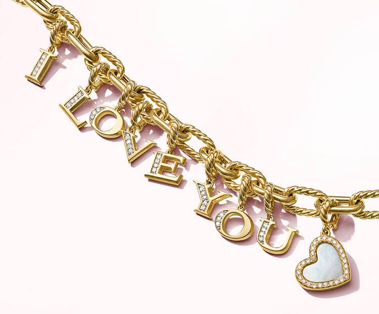 An image of a gold charm bracelet with letter amulets spelling I Love You.