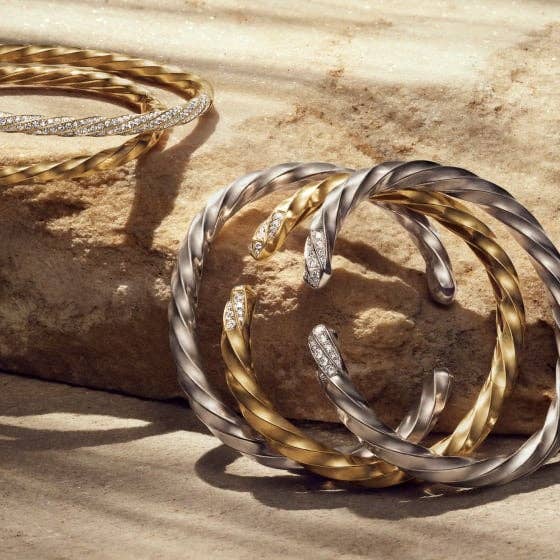 Multiple silver and gold bracelents from the David Yurman Cable Edge® collection.