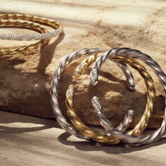 Multiple silver and gold bracelents from the David Yurman Cable Edge® collection.