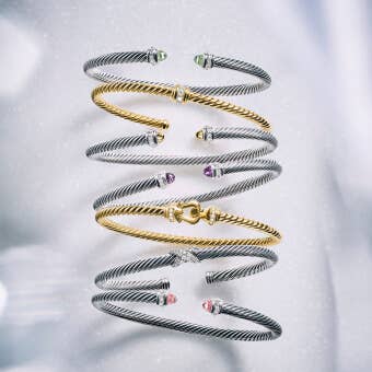 A variety of David Yurman cable bracelets in silver and gold.